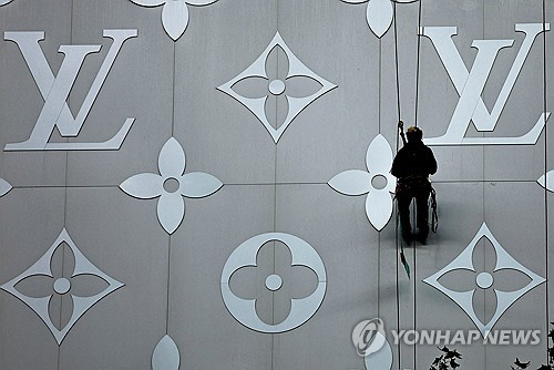 지난달 16일(현지시간) 프랑스 파리 샹젤리제의 루이비통 매장 외벽에서 한 노동자가 작업을 하고 있다. 로이터 연합뉴스